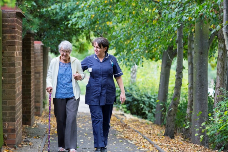 middle age woman helping elderly woman walk